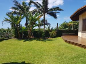 un patio trasero con palmeras y una terraza de madera en Casa da Márcia - Guarda do Embaú, en Guarda do Embaú