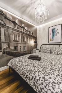 ルブリンにあるArtist Apartamentのベッドルーム(白黒のベッド1台、シャンデリア付)