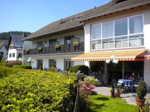 a house with a balcony with a table and chairs at Hotel Pension Haus Berghof in Hellenthal