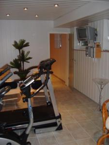een kamer met een fitnessruimte met een loopband en een tv bij Hotel Pension Haus Berghof in Hellenthal