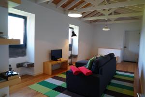 ein Wohnzimmer mit einem schwarzen Sofa und einem TV in der Unterkunft Casa do Cedro do Mato in Terra Alta