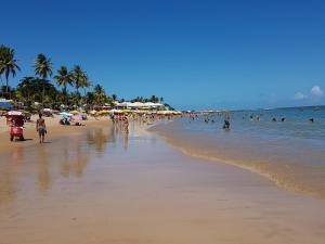 a beach with a lot of people in the water at Casa da Praia in Guarajuba
