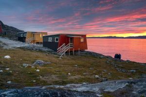 Deux maisons sur une colline à côté d'une nappe d'eau dans l'établissement Inuk Hostels, à Nuuk
