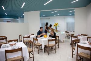 un groupe de personnes assises à table dans un restaurant dans l'établissement Hotel Santa Lucia, à Guardia Piemontese Terme