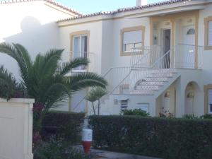 a white house with stairs and a palm tree at Apartment Oásis Comfort in Portimão