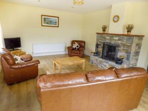 sala de estar con sofá de cuero y chimenea en Maison de Kilbride Finney Clonbur Mayo, en Clonbur