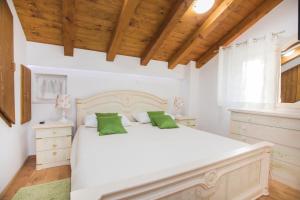 a bedroom with a large white bed with green pillows at Apartments Nove Crkve in Šibenik