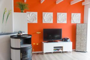 a living room with a tv and orange wall at Ferienwohnung "schöner Wohnen" in Westerstede