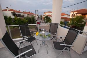 eine Terrasse mit einem Glastisch und Stühlen auf dem Balkon in der Unterkunft Kentrikon Suites in Polychrono