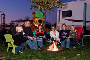 un grupo de personas sentadas alrededor de un fuego en Yogi Bear's Jellystone Park Camp-Resort Wisconsin Dells, en Wisconsin Dells