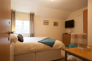 1 dormitorio con cama, ventana y mesa en West View Lodge en Basingstoke