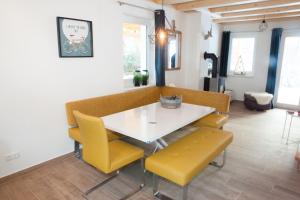 a dining room with a white table and yellow chairs at Ferienhäuser Glück Auf, Sauna, Hottubs in Arnoldstein