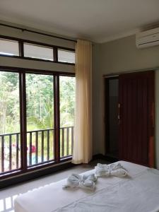 a bedroom with a bed and a large window at Kri Homestay in Kuta Lombok