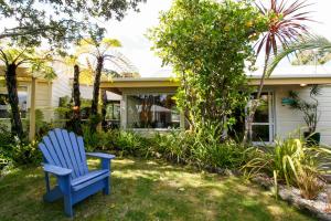 a blue chair sitting in the yard of a house at Tatahi Cove Back Packer in Hahei