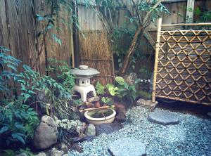 een tuin met een vogelbad en een hek bij Murasakino Guesthouse in Kyoto