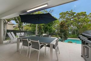 una mesa y sillas con una sombrilla en el patio en Headland Views Apartments, en Noosa Heads