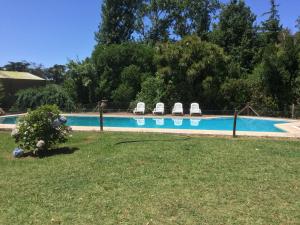 a swimming pool with chairs in a yard at Los 12 Robles in Batán