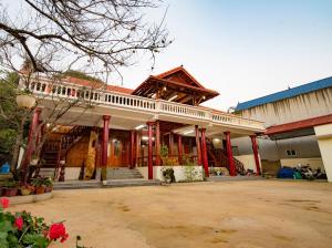 ein großes Gebäude mit roten Säulen und einer Veranda in der Unterkunft Moc Chau Town - Homestay in Mộc Châu