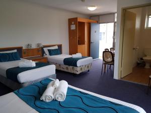 a hotel room with two beds with towels on them at The Q Motel Rockhampton in Rockhampton
