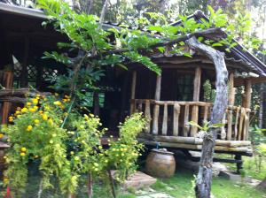 a wooden bench in front of a house with plants at Koh Kood Little Hut in Ko Kood