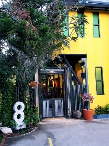 a yellow building with a gate with the number eight at Baan Baimai Boutique Room in Phra Nakhon Si Ayutthaya