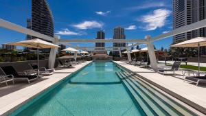 a pool on the roof of a building with chairs and umbrellas at Avani Broadbeach Residences in Gold Coast