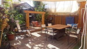 a wooden deck with a wooden table and chairs at Casa Rosa in Eilat