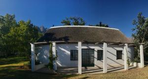 an old house with a thatched roof with a yard at Fisaasbos in Tulbagh
