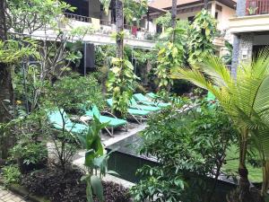 a resort with a pool with chairs and trees at Yulia 1 in Sanur