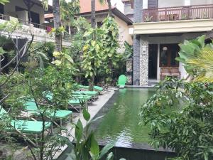 a pool in the courtyard of a building with green chairs at Yulia 1 in Sanur