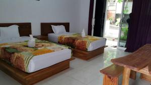 two beds sitting in a room with a window at Jo Homestay in Selong Belanak