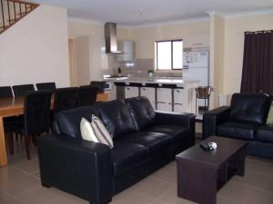 a living room with a black couch and a kitchen at Relax On Par in Port Hughes