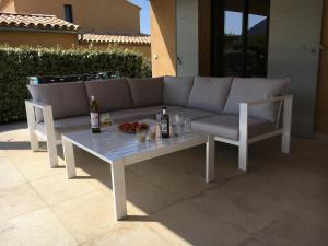 a couch and a table with bottles and drinks on a patio at Villa Le Grimpeur Malaucène in Malaucène