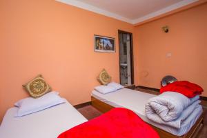 2 camas en una habitación con paredes de color naranja en Panauti Community Homestay, en Panaoti