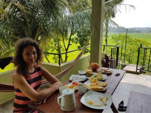 a woman sitting at a table with a plate of food at Rice Field View Home Stay in Tangalle