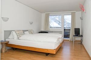 a bedroom with a bed and a television and a window at Chamanna Bed & Breakfast in Arosa