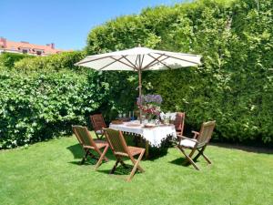 une table et des chaises sous un parasol dans l'herbe dans l'établissement Apartamento Sopiedra, à Nueva de Llanes