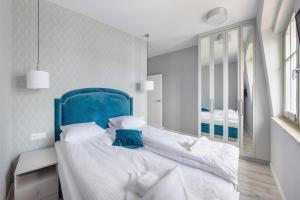 een slaapkamer met een groot bed met een blauw hoofdeinde bij Apartamenty Sun & Snow Na Monte Cassino in Sopot