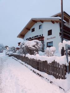 a house with a fence covered in snow at Haus Elisabeth in Nova Ponente