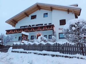 une maison avec une clôture recouverte de neige dans l'établissement Haus Elisabeth, à Nova Ponente