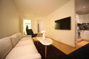 a living room with a couch and a table and a tv at BraMy Apartments The Bucks Villa in Tromsø