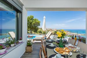 a balcony with a table with food and a view of the ocean at Contessa del Mare - Beachfront Living by etouri in Panormos Rethymno
