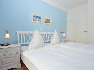 ein Schlafzimmer mit einem weißen Bett und einer blauen Wand in der Unterkunft Haus Möwe - Apt. 013 in Ostseebad Sellin