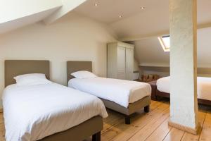 two beds in a room with white walls and wooden floors at Le Coeur des Choses in Escalles