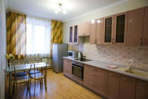 una cocina con armarios de madera, mesa y sillas en квартира на Торосова, en Abakán