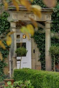 Risley Hall Hotel في Risley: باب امامي أبيض لبيت به ivy