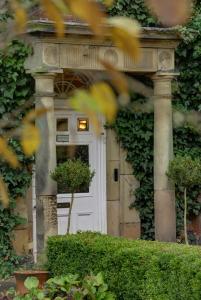 a white front door of a house with ivy at Risley Hall Hotel in Risley