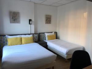 una camera con due letti con cuscini gialli di Les Initiés a Rouen