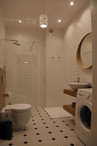 a bathroom with a toilet and a sink and a washing machine at Grey Apartments Kościuszko in Krakow