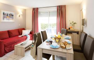 a living room with a table and a red couch at Résidence Odalys Les Hauts de Salavas in Salavas